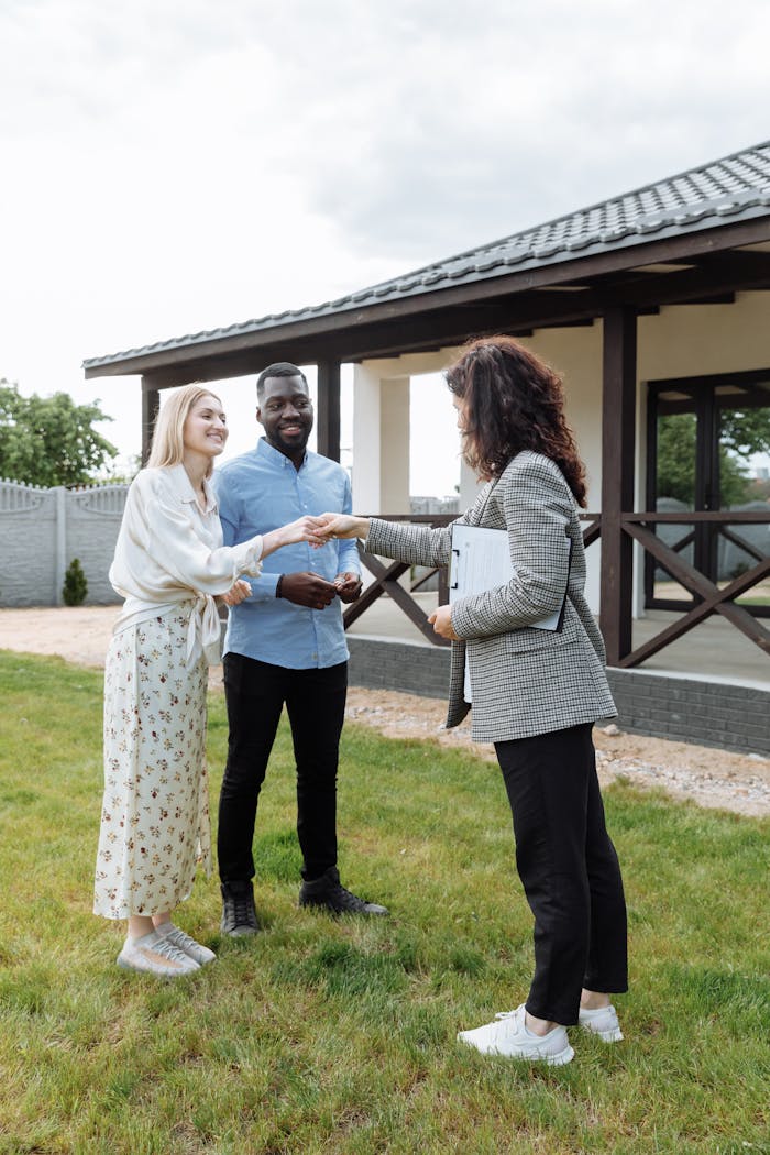 A realtor finalizes a home sale with a handshake agreement, welcoming new homeowners to their property.